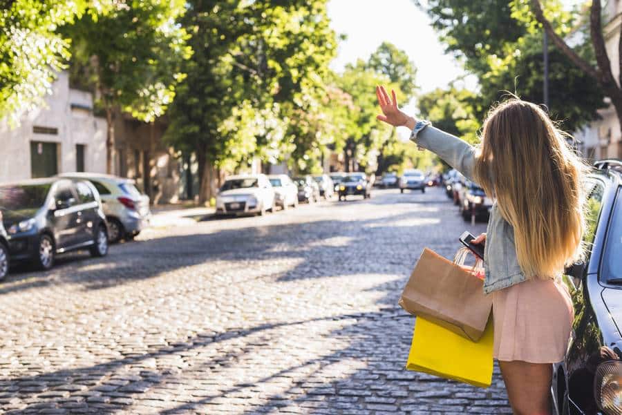 Eine Frau schwenkt ihre Einkaufstüten vor ihrem Taxi Achern.