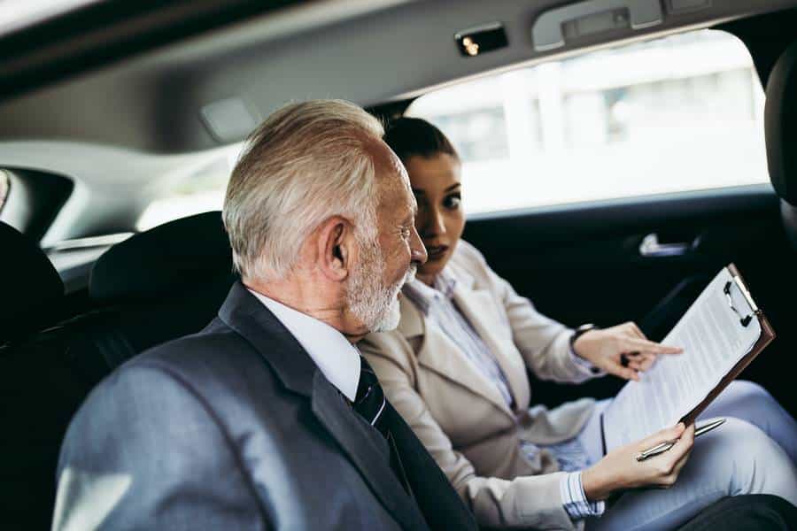 Ein Mann und eine Frau sitzen mit einem Klemmbrett auf dem Rücksitz eines Taxis.