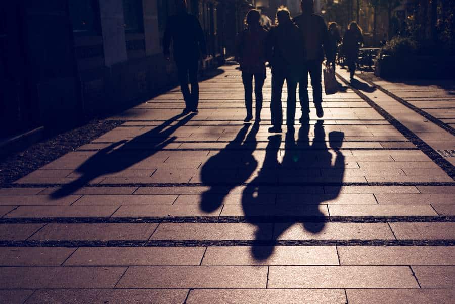Schatten von Menschen, die im Beisein von Taxi Datteln einen Bürgersteig entlanggehen.