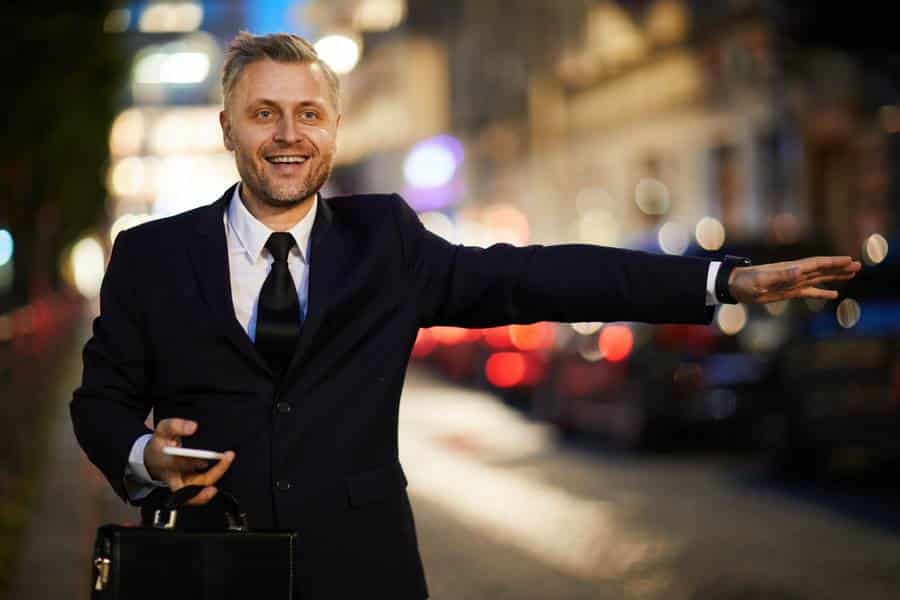 Ein Mann im Anzug zeigt nachts auf der Straße auf sein Handy, möglicherweise auf der Suche nach einem Taxi in Dessau-Roßlau.