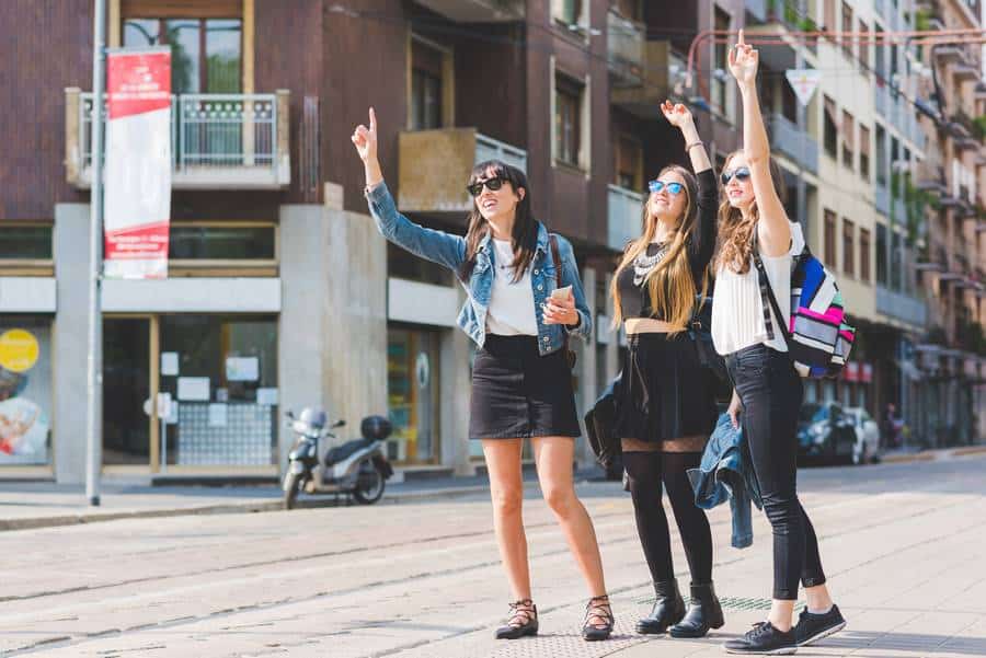 Drei junge Frauen stehen auf der Straße und wedeln mit den Armen und versuchen, in Fürstenfeldbruck ein Taxi zu rufen.