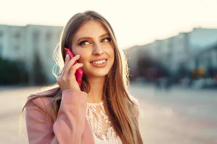 Eine junge Frau telefoniert in einem Taxi mit einem rosa Handy.