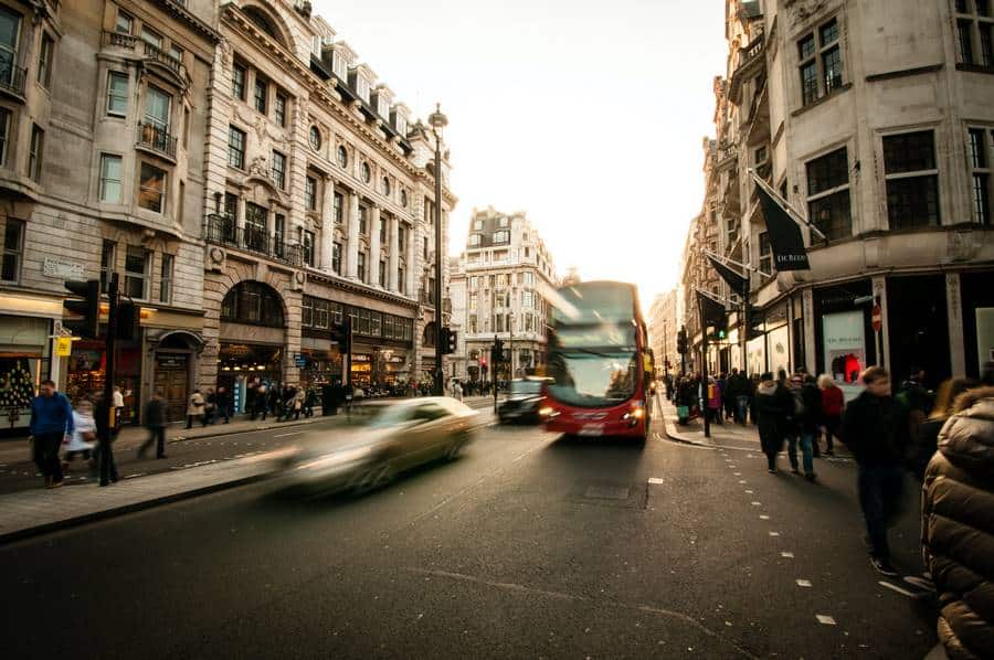 Ein Doppeldeckerbus fährt eine Straße in London entlang, im Hintergrund ein Taxi.