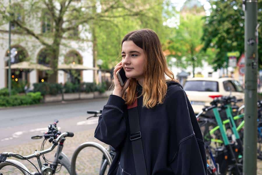 Eine Frau telefoniert, während sie eine Stadtstraße entlang geht.